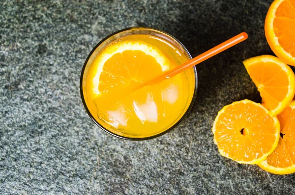 Χυμό πορτοκάλι με φέτες φρούτων στο πέτρινο τραπέζι — Φωτογραφία Αρχείου