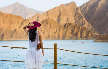 Woman enjoying Hatta Dam Lake scenery in eastern Dubai, UAE clipart