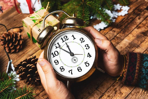 Person holding a vintage clock in festive environment
