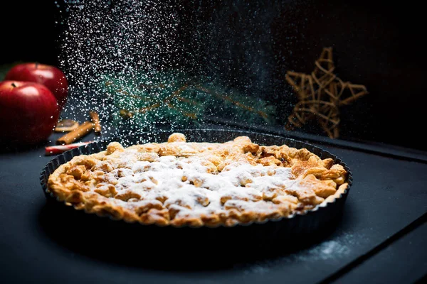 Apple pie sprinkled with sugar on a festive decorated table