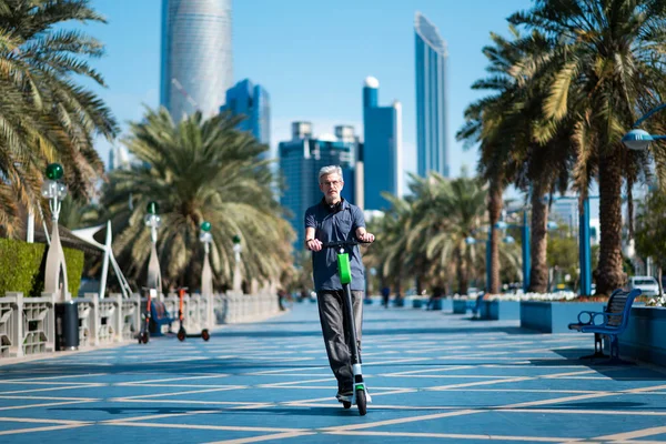 Senior utilizzando scooter elettrico per il trasporto in una città moderna — Foto Stock