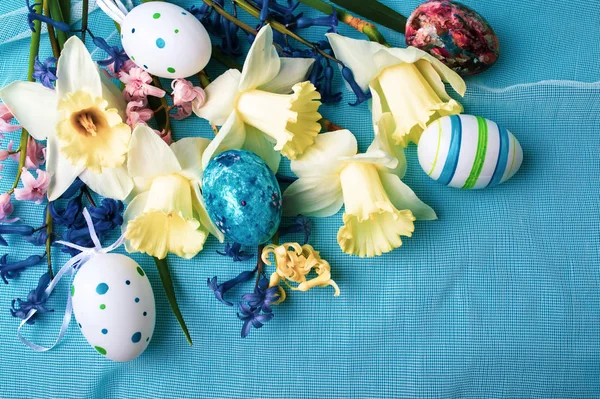 Easter eggs and narcissus flowers on blue — Stock Photo, Image