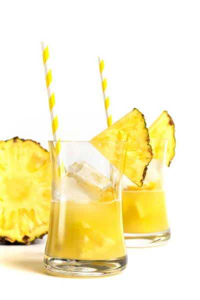 Ένα ποτήρι χυμό ανανά με καλαμάκι και φέτες ανανά είναι — Φωτογραφία Αρχείου