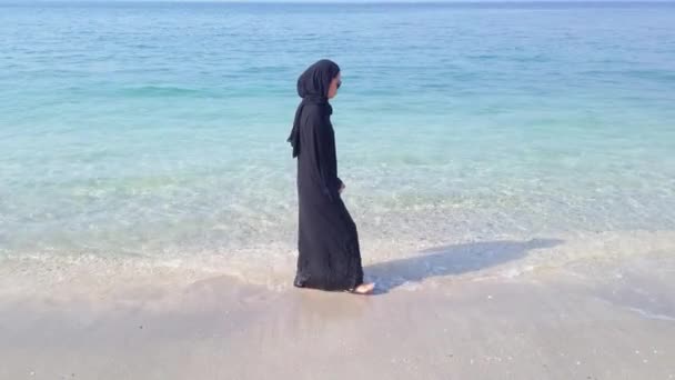 海岸沿いを歩くヒジャーブを身に着けているイスラム教徒の女性 — ストック動画