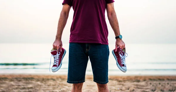 Muž Drží Tenisky Pláži Soumraku — Stock fotografie