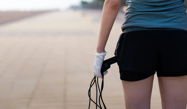 Kobieta Trzymająca Skakankę Ochronnych Rękawiczkach Chirurgicznych Bezpiecznego Treningu Świeżym Powietrzu — Zdjęcie stockowe