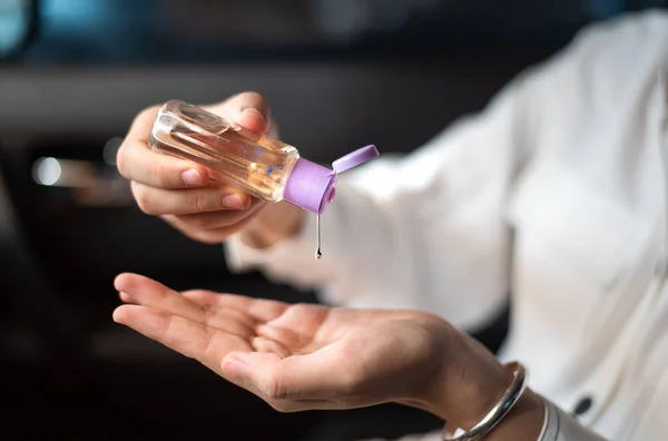 Woman using hand sanitizer in the car for hands disinfection while outdoors to prevent virus spread during the pandemic