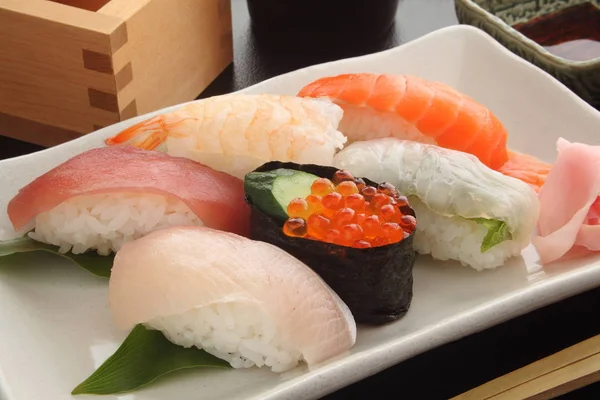 Gemischte Sushi-Platte auf weißem Teller mit Sake, japanischem Essen — Stockfoto