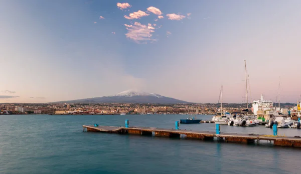 Skyline of Catania and its harbor with snowy volcano Etna in background after the sunset — Stock Photo, Image