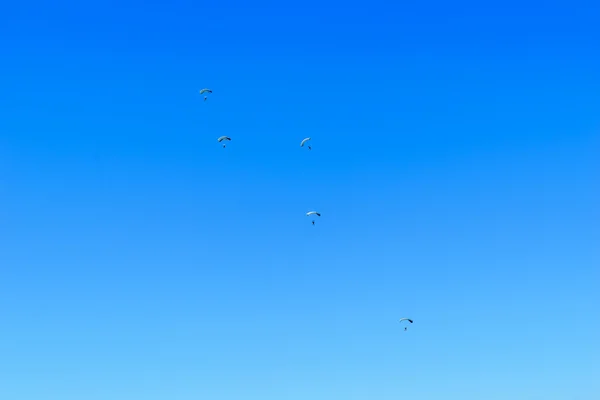 Fallskärmsjägare ner till jorden på blå klar himmel bakgrund — Stockfoto