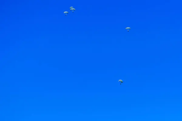 Paratroopers descend to earth on the blue clear sky background — Stock Photo, Image