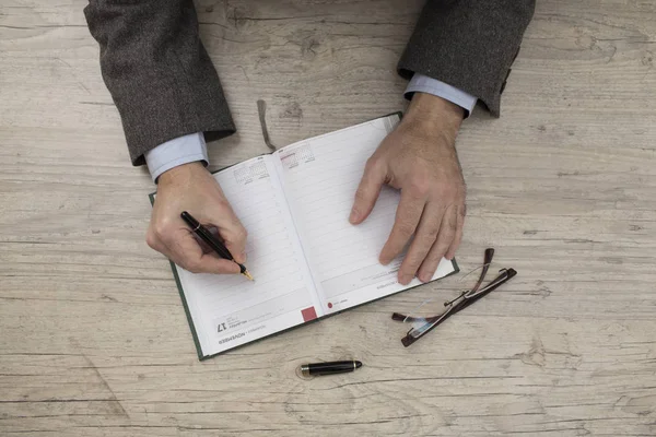 Biznesmen w kurtce pisze w swoim pamiętniku — Zdjęcie stockowe