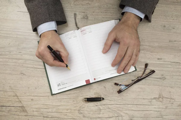 A businessman in a jacket writes in his diary — Stock Photo, Image