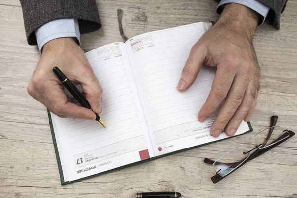 Ein Geschäftsmann in Jacke schreibt in sein Tagebuch — Stockfoto