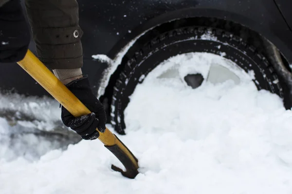 Een man een auto van een schop sneeuw schoonmaken — Stockfoto