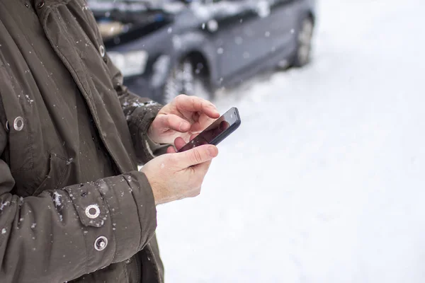 driver in the winter on the road calls for help by phone