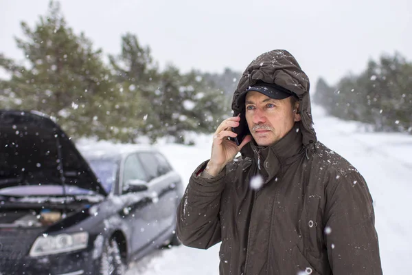 driver in the winter on the road calls for help by phone