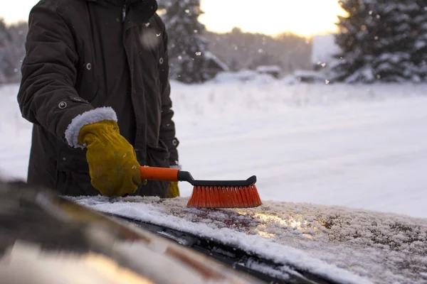Мужчина чистит машину от снега — стоковое фото