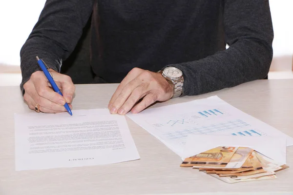 Un hombre de negocios firma un contrato y da dinero en efectivo . — Foto de Stock