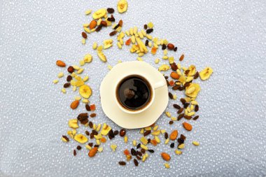 Masanın üzerinde bir fincan kahve ve fındık var..