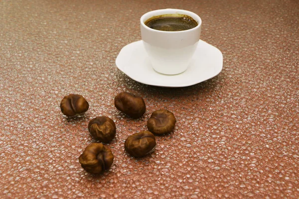 A cup of coffee, nuts and chestnuts are scattered around. — Stock Photo, Image