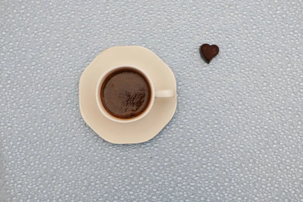 Κοντινό πλάνο - ένα φλιτζάνι καφέ, δίπλα σε δύο σοκολάτες σε σχήμα καρδιάς. — Φωτογραφία Αρχείου