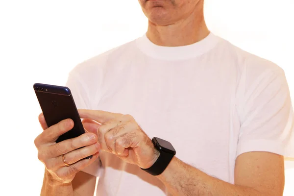 Close-up - homem de negócios em uma camiseta branca segura um smartphone em — Fotografia de Stock