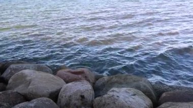           Güneşli havada, dalgalar taştan bir deniz kıyısında kırılır..