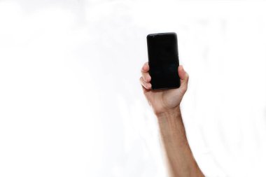 Beyaz arka planda uzanan bir el telefonunda.