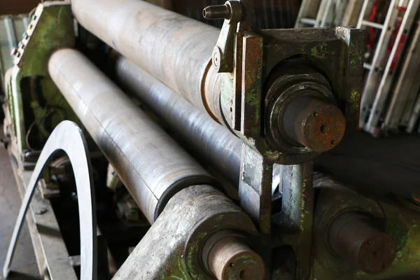 A man works on old equipment in a factory. Old equipment. Safe work. Remote Control. Saw for metal. The mechanism for rolling metal.