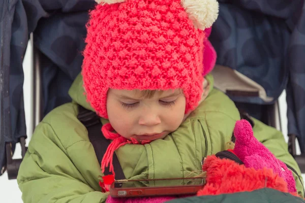 Dítě vypadá v mobilním telefonu na kresleném seriálu — Stock fotografie