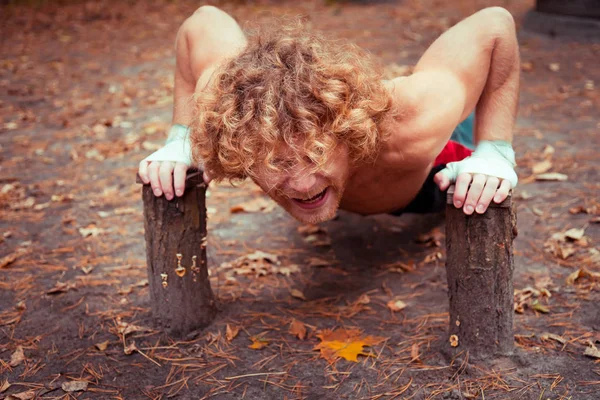 Zelfgemaakte speeltuin. Atleet zwaait de armspieren. — Stockfoto