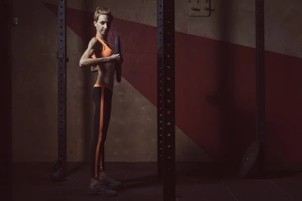 Salle de gym. Elle s'accroupit avec un haltère — Photo