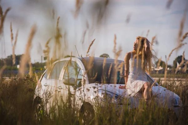 Una ragazza siede sul cofano di una macchina — Foto Stock