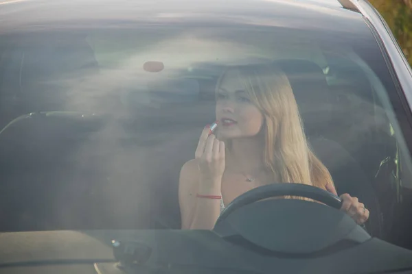Dziewczyna maluje usta szminką podczas jazdy. — Zdjęcie stockowe