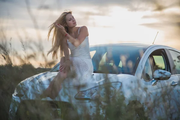 Uma menina senta-se no capô de um carro — Fotografia de Stock