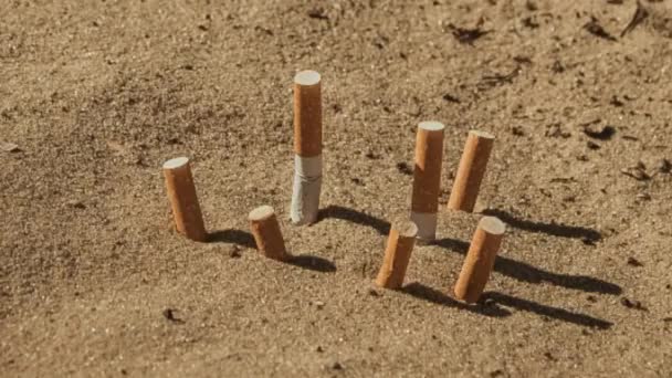 Cigarettacsikkek a homokban — Stock videók