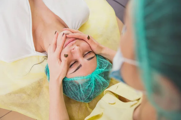 Ansiktsmassage. Flickor gör ansiktsmassage i skönhetssalongen — Stockfoto