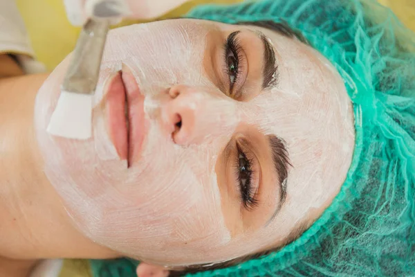 Cosmetic face mask. Girl in a beauty salon make a mask for the f — Stock Photo, Image