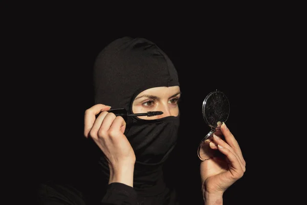 Дівчина злочинець. Дівчина в чорній масці малює вії . — стокове фото