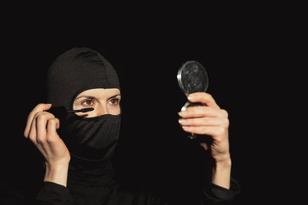 Meisje de dader. Het meisje in een zwart masker verf wimpers. — Stockfoto