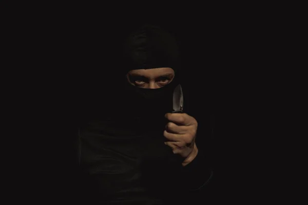 Een man in een zwart masker met een mes in zijn hand. — Stockfoto