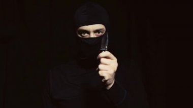 Siyah maskeli bir adam elinde bir bıçak ile.