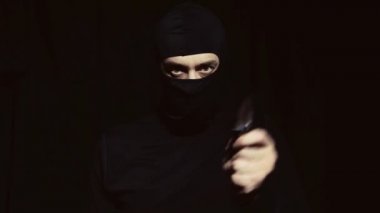 Siyah maskeli bir adam elinde bir bıçak ile.