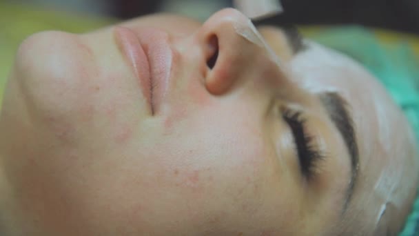 Kosmetiska ansiktsmask. Flicka i en skönhetssalong gör en mask för ansiktet — Stockvideo