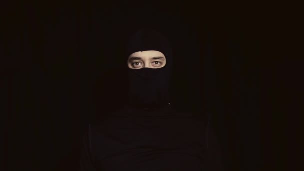 Een man in een zwart masker met een mes in zijn hand. — Stockvideo