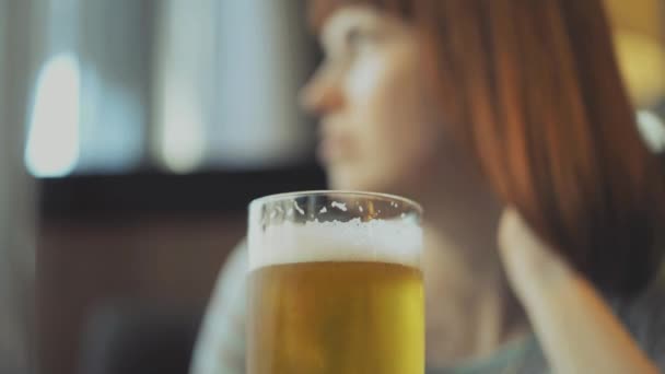 En flicka sitter på ett café dricka öl och titta in telefonen — Stockvideo