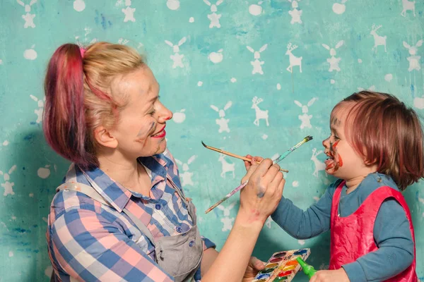 Mamá y el niño dibujan pinturas de la cara del otro . — Foto de Stock