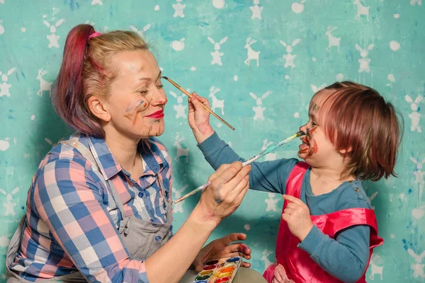 Mom and the child draw paints of each other's faces. — Stock Photo, Image