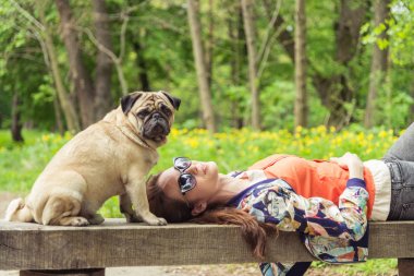 Pug doğurmak köpek. Bir kız bir köpek yeşil çimenlerin üzerinde yürüyor.